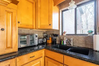 a kitchen with wooden cabinets and a sink and a microwave at Twin Pines Retreat Hot Tub Theater Room Fire in East Stroudsburg
