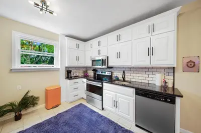 a kitchen with white cabinets and a blue rug at Comfort, Fun, and Retro Retreat in Royersford