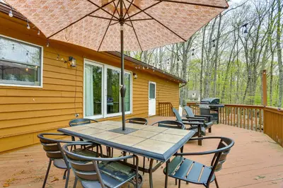 a table and chairs on a deck with an umbrella at half Mi to Boat Ramp Lake Wallenpaupack Retreat! in Lakeville