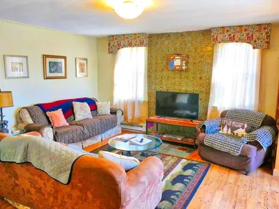 a living room with couches and a flat screen tv at Lakefront Cabin Rental with Incredible Sunsets on Lake Wallenpaupack, Pennsylvania in Hawley