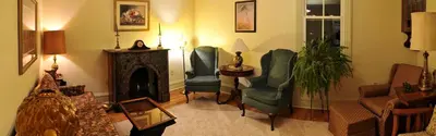 a living room with two chairs and a fireplace at Spacious Cottage Rental with Creek Views near Harrisburg and Hershey, Pennsylvania in Middletown