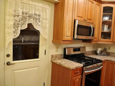 a kitchen with a door and a stove and microwave at Spacious Cottage Rental with Creek Views near Harrisburg and Hershey, Pennsylvania in Middletown