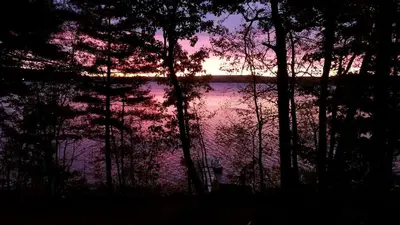 a sunset over a body of water with trees at Lakefront Vacation Rental with Superb Views over Lake Wallenpaupack in Hawley, Pennsylvania in Hawley