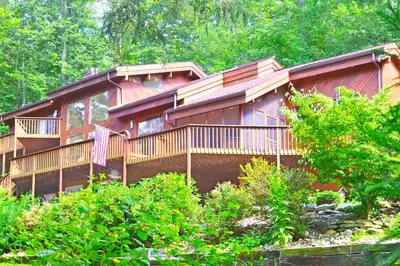 a large wooden cabin in the woods with trees at Stunning Cabin Rental with a Hot Tub Overlooking Fishing Creek near Sproul State Forest, Pennsylvania in Mill Hall