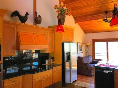 a kitchen with wooden cabinets and a stainless steel refrigerator at Stunning Cabin Rental with a Hot Tub Overlooking Fishing Creek near Sproul State Forest, Pennsylvania in Mill Hall