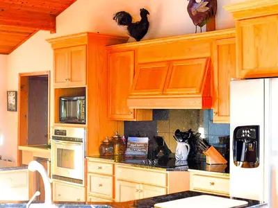 a kitchen with wooden cabinets and chickens on the wall at Stunning Cabin Rental with a Hot Tub Overlooking Fishing Creek near Sproul State Forest, Pennsylvania in Mill Hall