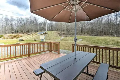 a wooden deck with a picnic table and an umbrella at Remote Ski Rentals for a Gorgeous Pennsylvania Retreat in Pleasant Mount