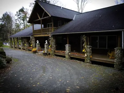 a large building with a porch and a walkway in front at Spacious Villa Rental with a Pool for a Large Group near Catskill Mountains, New York in Fishs Eddy