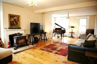 a living room with a fireplace and a piano at 27-Person Luxury Villa Rental in Hudson Valley, New York in Monroe
