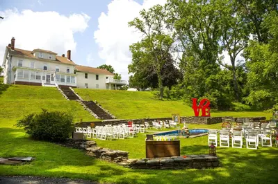 a wedding ceremony on a hill with white chairs at 27-Person Luxury Villa Rental in Hudson Valley, New York in Monroe