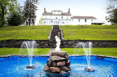 a fountain in front of a house with a building at 27-Person Luxury Villa Rental in Hudson Valley, New York in Monroe