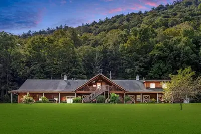 a house with a green lawn in front of a mountain at Fantastic Secluded Rental for a Large Group Getaway near East Branch, New York in Fishs Eddy