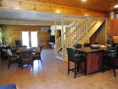 a living room with chairs and tables and a staircase at Fantastic Secluded Rental for a Large Group Getaway near East Branch, New York in Fishs Eddy