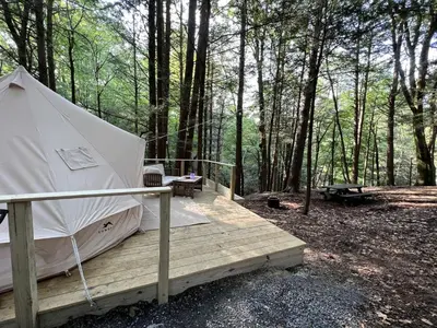 a tent on a wooden deck in the woods at Amazing Equipped Bell Tent Nestled Among Nature in New York in Kerhonkson