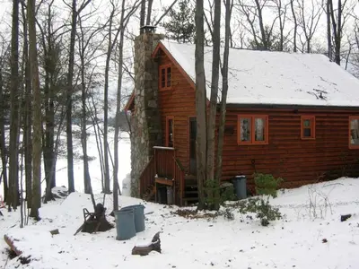 a log cabin in the woods with snow at Idyllic Waterfront Log Cabin in Wayne County Overlooking Lake Wallenpaupack, Pennsylvania in Lakeville