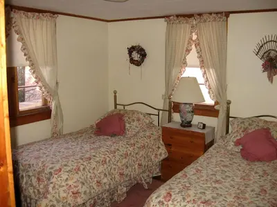 a bedroom with two beds and a table with a lamp at Idyllic Waterfront Log Cabin in Wayne County Overlooking Lake Wallenpaupack, Pennsylvania in Lakeville