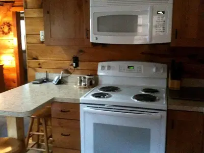 a kitchen with a white stove and a microwave at Idyllic Waterfront Log Cabin in Wayne County Overlooking Lake Wallenpaupack, Pennsylvania in Lakeville