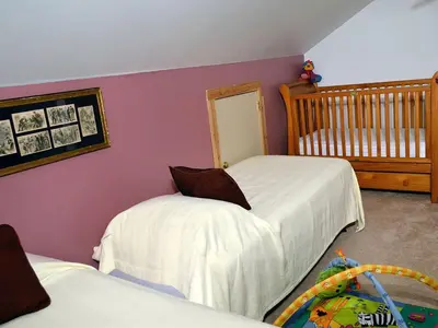 a childs bedroom with two beds and a crib at Enormous Family-Friendly Cabin Rental in Shawangunk Mountains, New York in Pine Bush