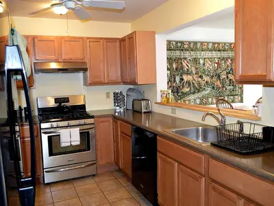a kitchen with wooden cabinets and a stove and a sink at Enormous Family-Friendly Cabin Rental in Shawangunk Mountains, New York in Pine Bush