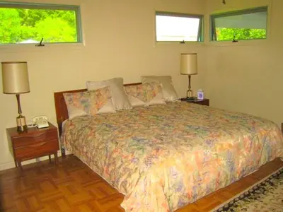a bedroom with a bed with two lamps and two windows at Peaceful Private Cabin on Crystal Lake near Elk Mountain, Pennsylvania in Clifford