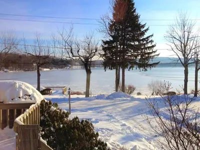 a snow covered yard with trees and a body of water at Peaceful Private Cabin on Crystal Lake near Elk Mountain, Pennsylvania in Clifford