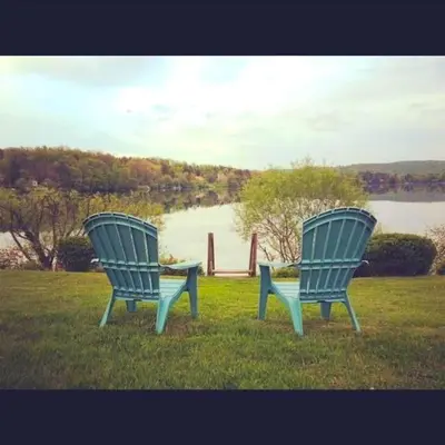 two blue chairs sitting in the grass near a body of water at Peaceful Private Cabin on Crystal Lake near Elk Mountain, Pennsylvania in Clifford