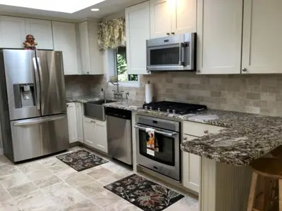 a kitchen with white cabinets and stainless steel appliances at Delightful Cottage Rental with Scenic Views near the Poconos, Pennsylvania in Tobyhanna