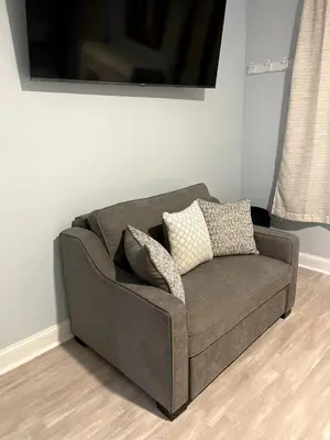 a brown couch sitting in a living room at Sweet Diamonds & Adventures 10 Mins To NYC in Union City