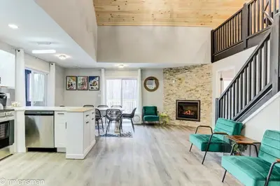 a living room with a staircase and a living room with green chairs at The Hut House 3BR 3BA Game Room Massage Chair in Lake Ariel