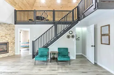 a living room with a staircase and green chairs at The Hut House 3BR 3BA Game Room Massage Chair in Lake Ariel