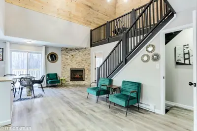 a living room with a staircase and green chairs at The Hut House 3BR 3BA Game Room Massage Chair in Lake Ariel