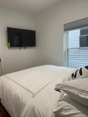 a bedroom with a bed with a flat screen tv on the wall at Cozy 3BR Retreat with Rooftop Near EWR & NYC Access in Newark