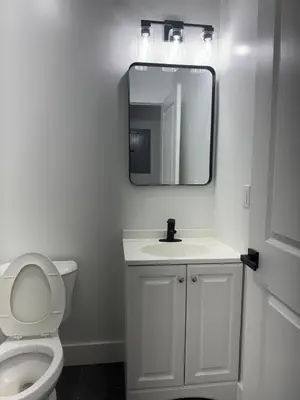 a bathroom with a white toilet and a mirror at Cozy 3BR Retreat with Rooftop Near EWR & NYC Access in Newark