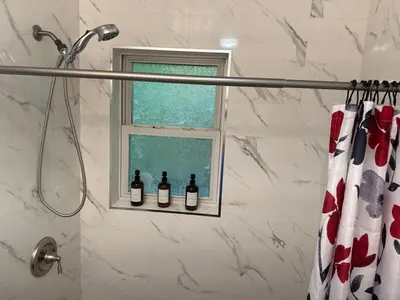 a window in a bathroom with three bottles of wine at Warm & Cozy Escape - NYC & NWK with Free Parking in Bayonne