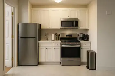 a kitchen with stainless steel appliances and white cabinets at Warm & Cozy Escape - NYC & NWK with Free Parking in Bayonne