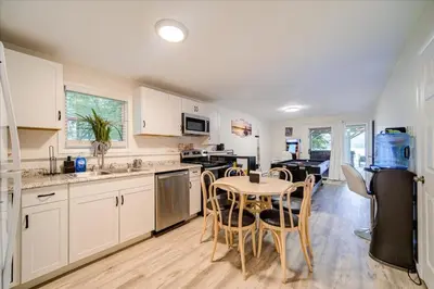 a kitchen with white cabinets and a table and chairs at Catskills Lakefront with Hot Tub, Sauna and Theater in Monticello