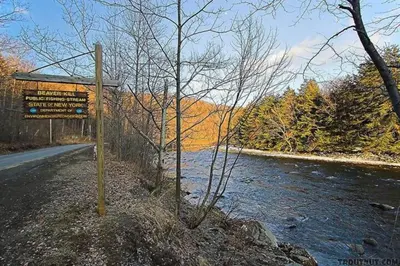 a sign on the side of a road next to a river at Catskills Lakefront with Hot Tub, Sauna and Theater in Monticello