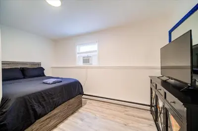 a bedroom with a bed and a flat screen tv at Catskills Lakefront with Hot Tub, Sauna and Theater in Monticello