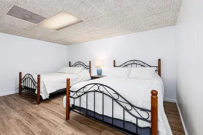 two beds in a bedroom with white walls and wood floors at Enola Trail Getaway - bikes, rural, BBQ ,King bed, patio in Pequea