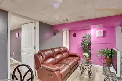 a living room with a leather couch and pink walls at 9 Mi to Midtown Convenient Harrisburg Apt in Harrisburg
