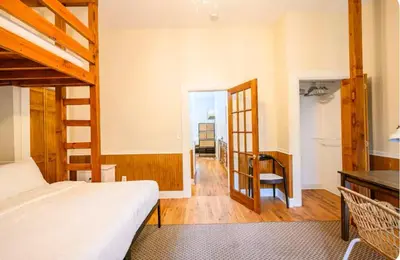 a bedroom with a bed and a desk and a staircase at Yard, Laundry, Large! Bonus Sleep Area in Jersey City