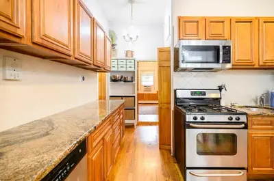 a kitchen with wooden cabinets and a stove top oven at Yard, Laundry, Large! Bonus Sleep Area in Jersey City