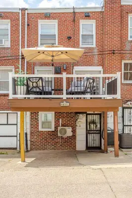 a balcony with chairs and an umbrella in front of a brick building at Staycation Suite in Philadelphia