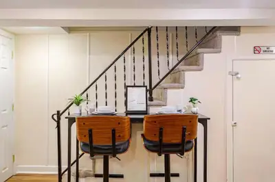 a room with a table with two chairs and a staircase at Staycation Suite in Philadelphia