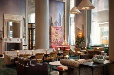 a lobby with chairs and tables and a fireplace at The Wall Street Hotel by Suiteness in New York