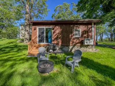 a log cabin with two chairs and a fire pit at Cozy Cabin Gateway with Pool and Firepit in Montgomery