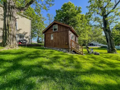 a small cabin in a yard with a tree at Cozy Cabin Gateway with Pool and Firepit in Montgomery