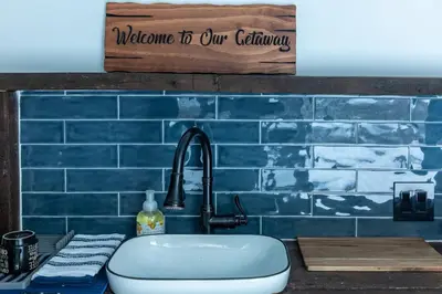 a kitchen with a sink and a blue tiled wall at Cozy Cabin Gateway with Pool and Firepit in Montgomery