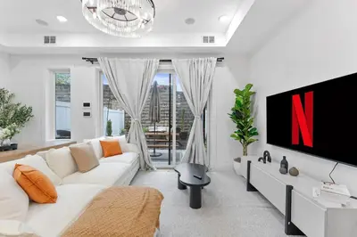 a living room with a white couch and a tv at Luxury 3BR Backyard Oasis Close to NYC FirePit in Jersey City