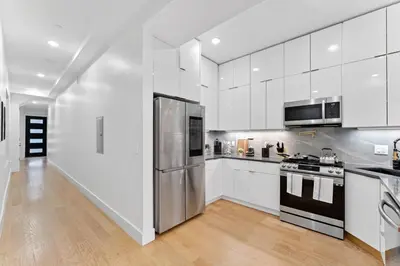 a kitchen with white cabinets and a stainless steel refrigerator at Luxury 3BR Backyard Oasis Close to NYC FirePit in Jersey City